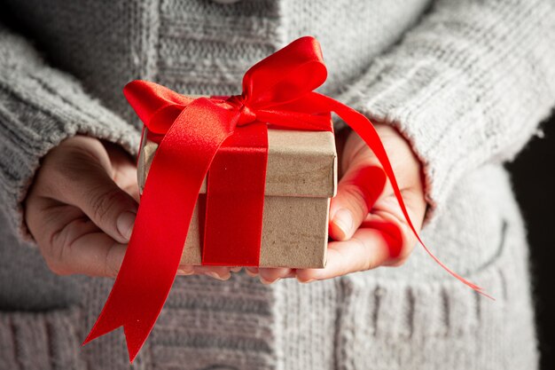 Woman's hand holding a gift box with red ribbon