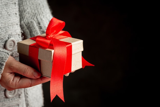 Woman's hand holding a gift box with red ribbon