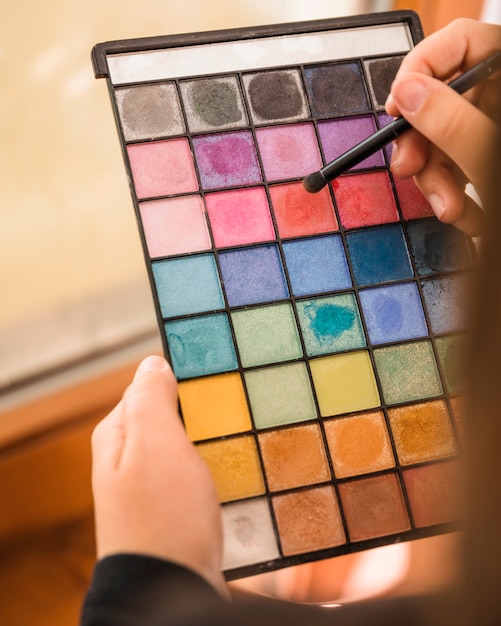Woman's hand holding palette of eye shadow powder