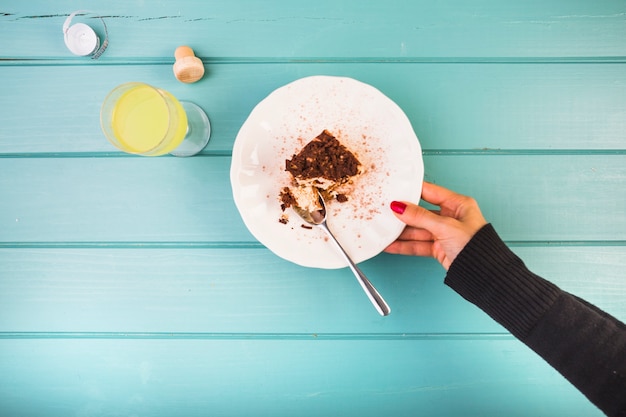 Foto gratuita piatto della mano della tenuta della donna di pasticceria con la bevanda sul tavolo