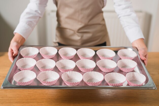 空のカップケーキケースのトレイを持っている女性の手