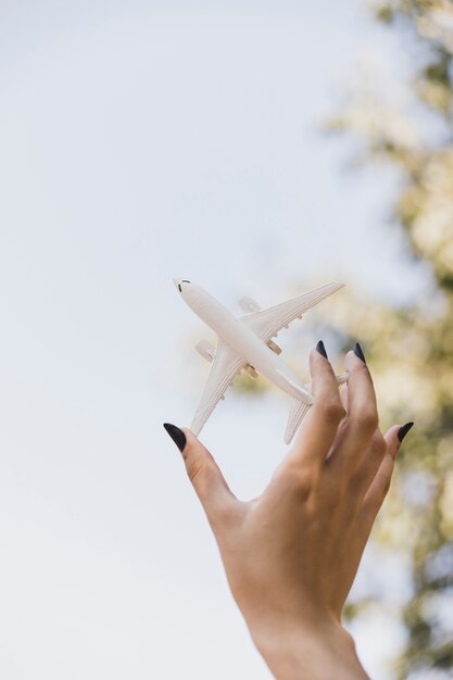 Woman's hand holding white miniature airplane