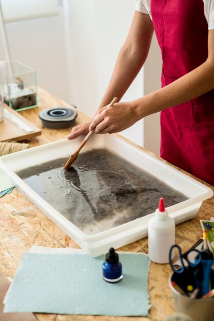 Woman's hand making paper pulp in container