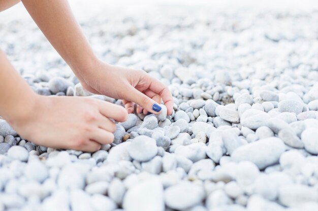 Woman's hand picking up pebbles at beach