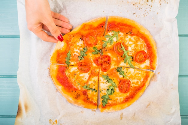 Woman's hand picking up slice of pizza