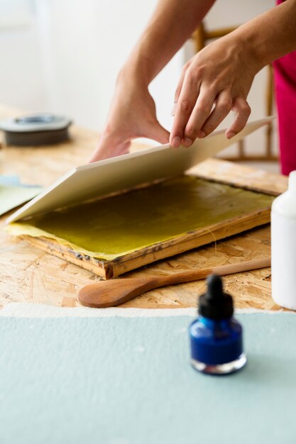 Woman's hand placing cover over mold for making paper