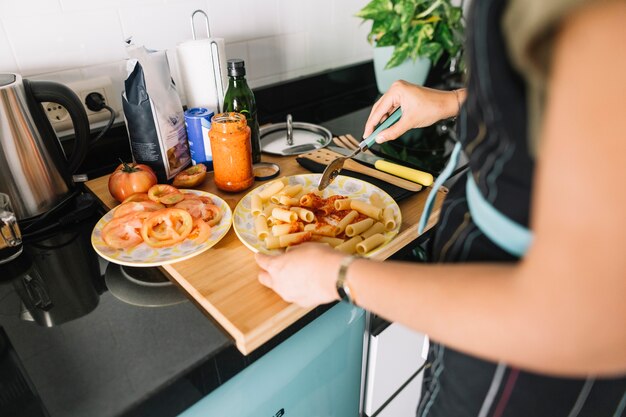 Woman's hand preparing delicious pasta on kitchen counter
