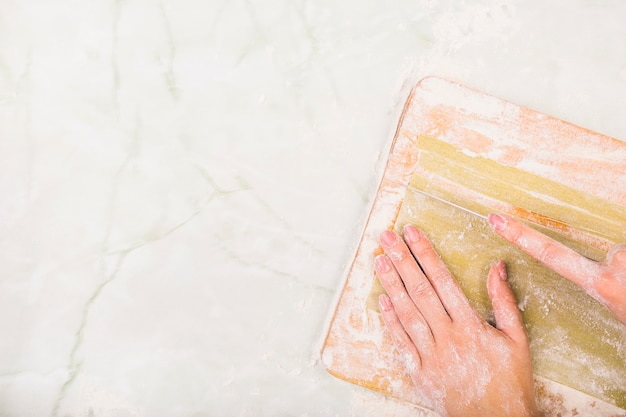 Woman's hand preparing pasta on chopping board