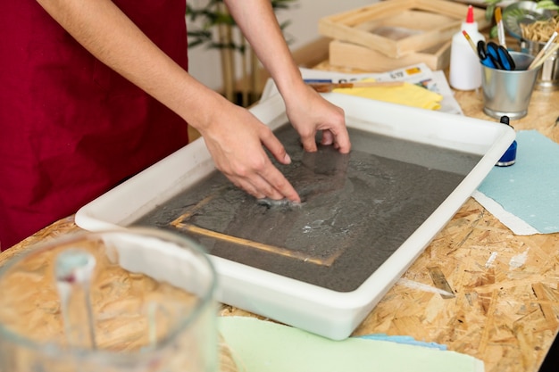 Woman's hand putting mold in paper pulp