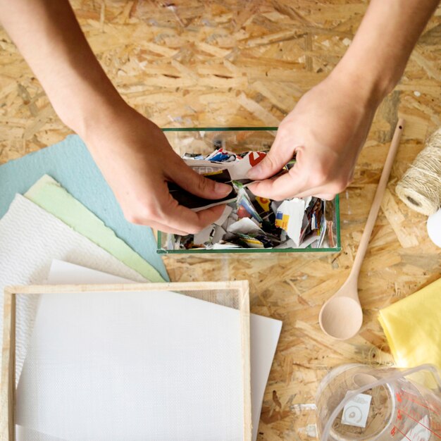 Woman's hand putting torned paper into glass container