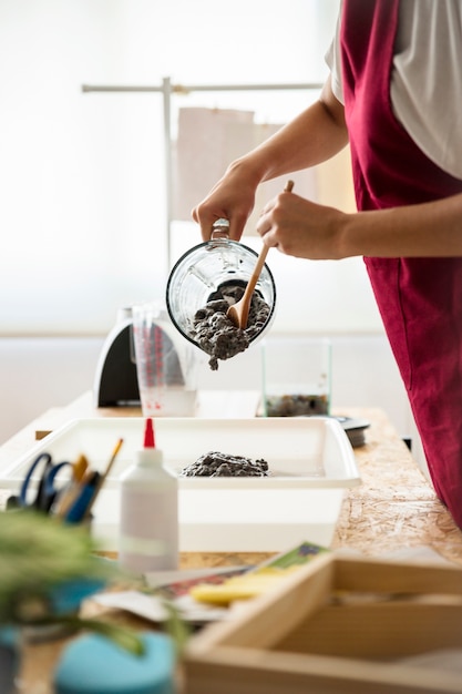 Free photo woman's hand removing paper pulp from blender in tray