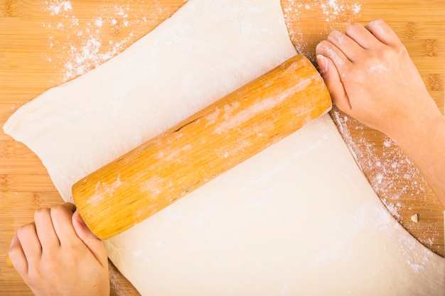 Woman's hand rolling dough with rolling pin