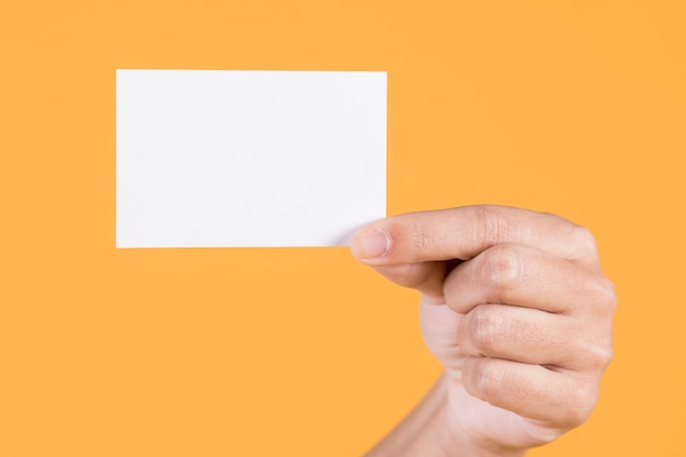 Woman's hand showing blank white visiting card against yellow background