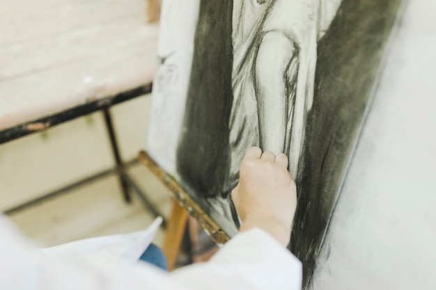 Woman's hand sketching female on canvas