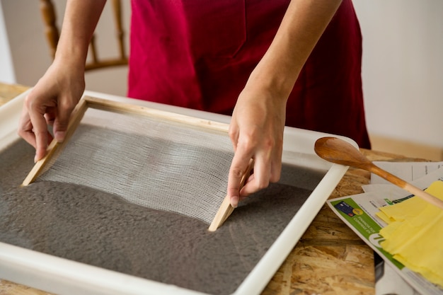 Woman's hand soaking mold in paper pulp