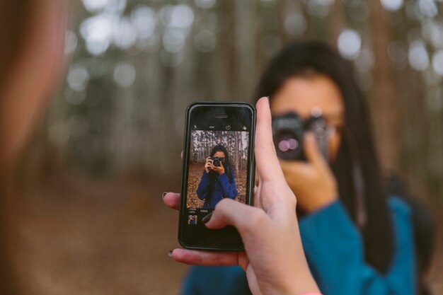 カメラを持っている彼女の友人の写真を撮っている女性の手