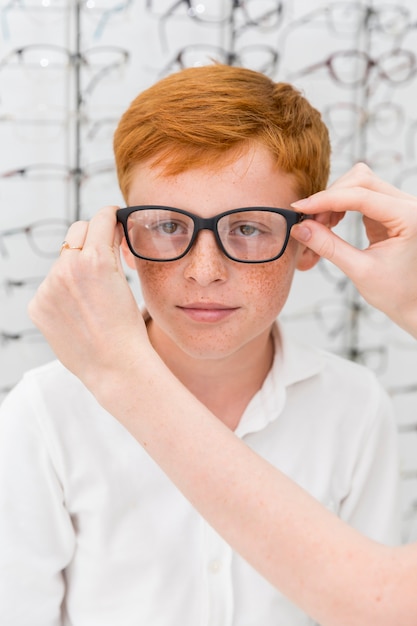 Foto gratuita spettacolo da portare della mano della donna al ragazzo nel negozio di ottica