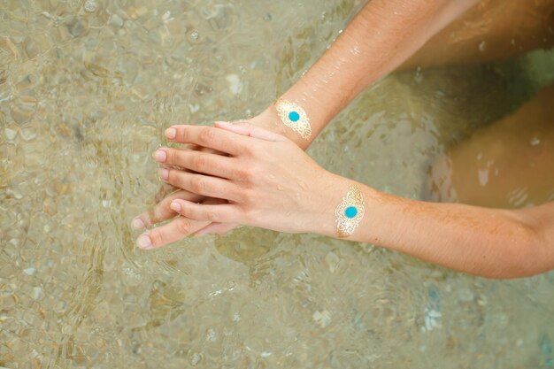 Woman's hands legs with sticker tatoo in the sea