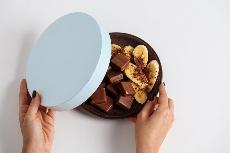 無料Photo 白のチョコレートとバナナのボックスを開く女性の手