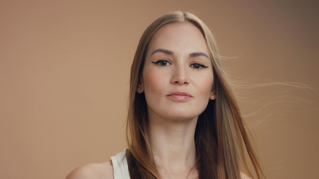 Woman's portrait in studio in beige tones blonde woman with long straight hair