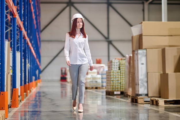 Woman in safety helmet walking on warehouse