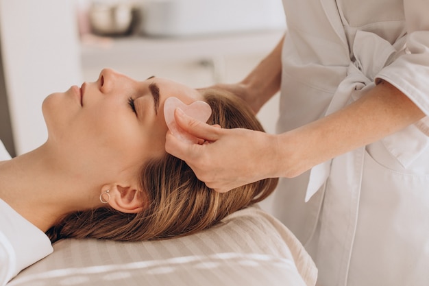 Woman in salon making beauty treatment with gua sha stone