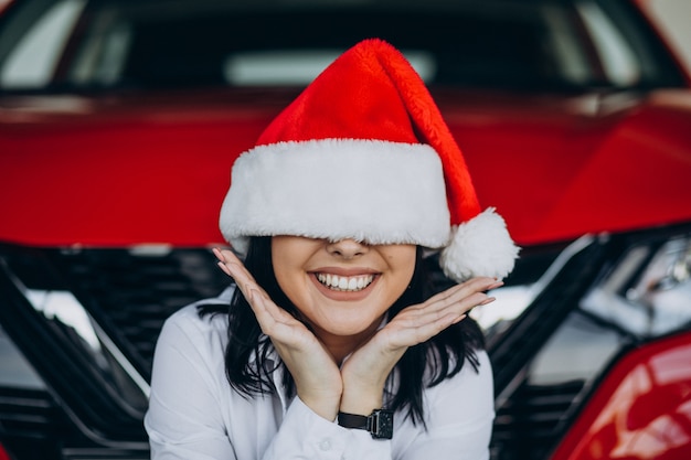 Free photo woman in santa hat on christmas in car showroom