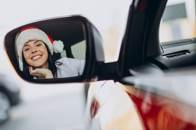 Woman in santa hat on christmas in car showroom