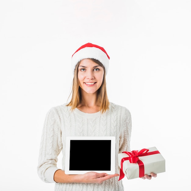 Free photo woman in santa hat holding tablet and gift box