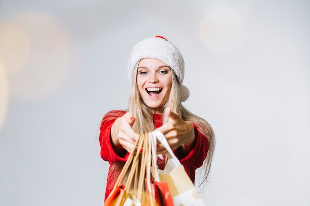 Free photo woman in santa hat with colourful shopping bags in hands