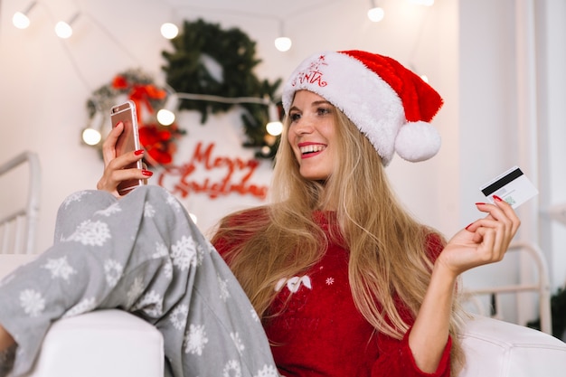 Женщина в шляпе Санта с телефоном и картой