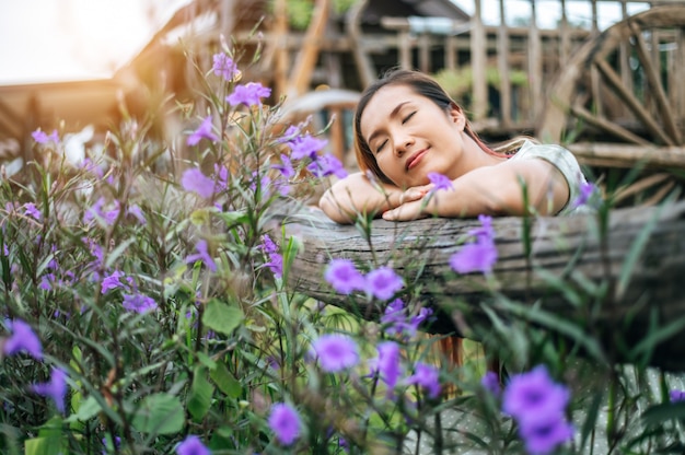 woman sat happily in the flower garden and laid her hands and towards the wooden fence