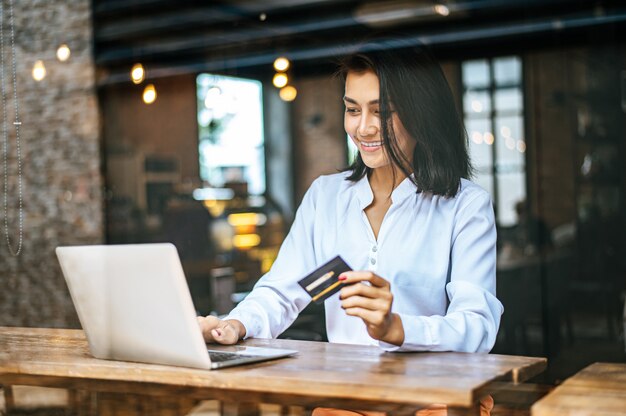 女性はラップトップで座って、カフェでクレジットカードで支払い