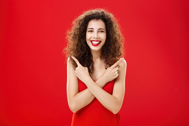 エレガントな赤いイブニングドレスでのんきで幸せな立ちを感じてどんな決断にも満足している女性...