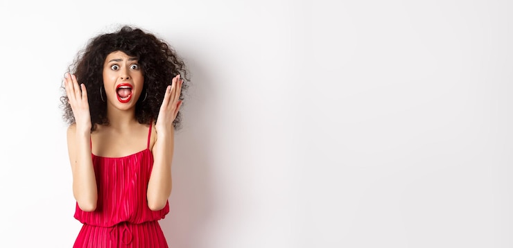 Free Photo woman scream in panic wearing red dress and shouting at camera with anxious face standing over white