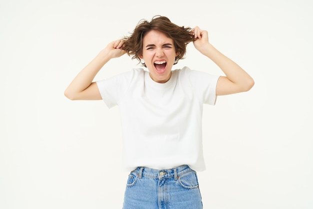 Free photo woman screams pulls out her hair and shouts stands frustrated angry and pissedoff stands over white