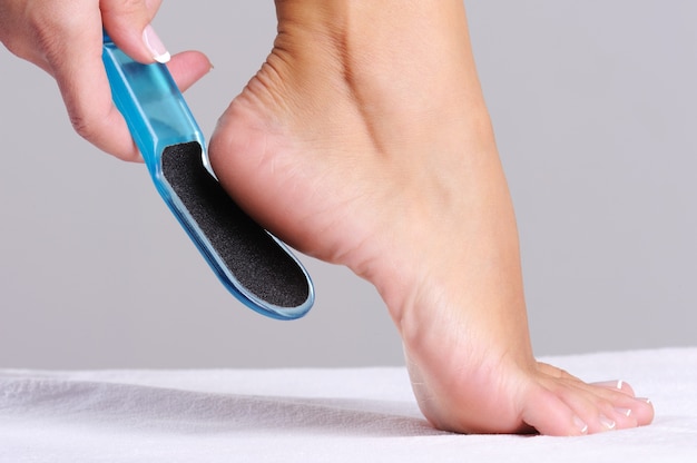 Woman scrubbing  heel in beauty salon use the   tool for pedicure
