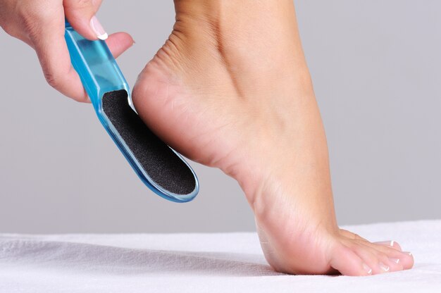 Woman scrubbing  heel in beauty salon use the   tool for pedicure