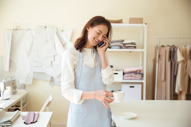 電話で話しているとコーヒーを飲む女性の仕立て屋