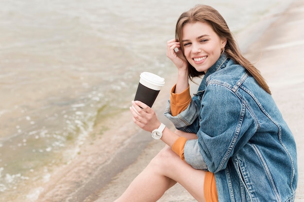 Free photo woman at seaside with coffee