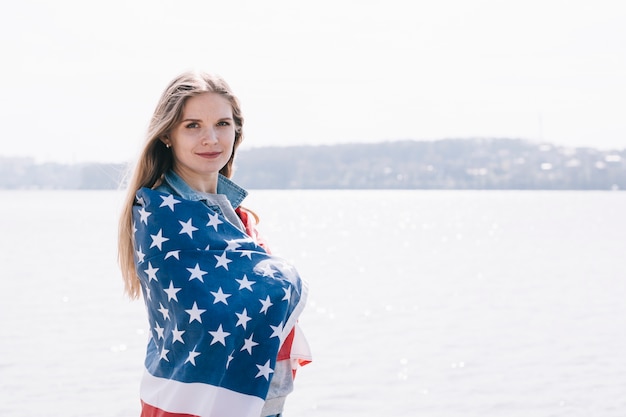 Woman seriously looking at camera wrapped in American flag