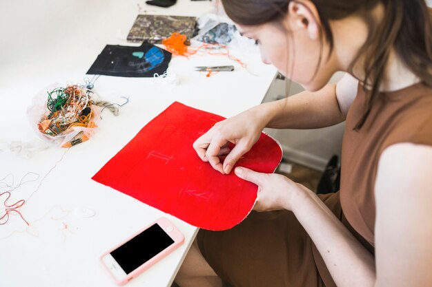 Woman sewing red cloth with needle