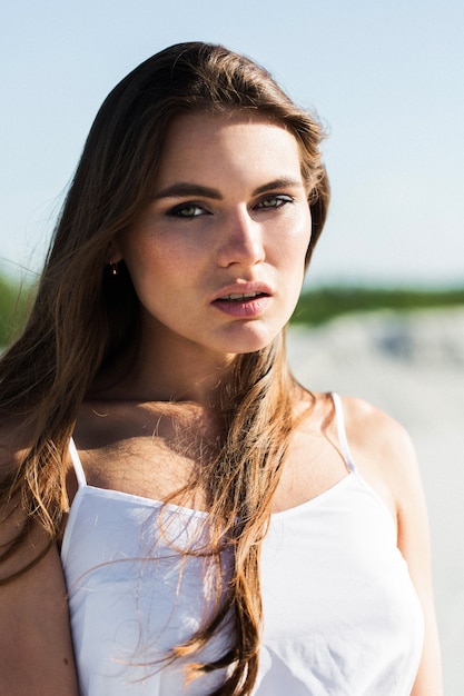 Woman shakes her long hair posing on the beach