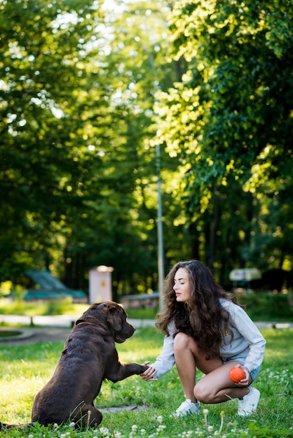 Foto gratuita donna che agita la zampa del suo cane in giardino