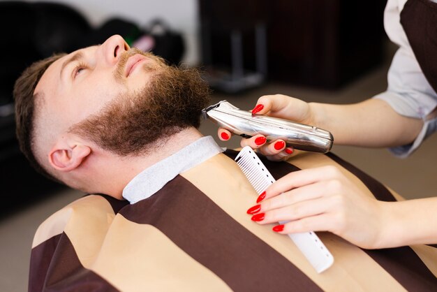 Woman shaving her client's mustache