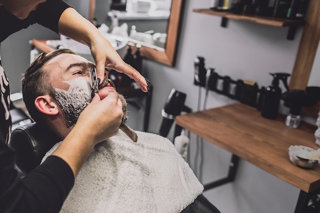 Free photo woman shaving man in salon