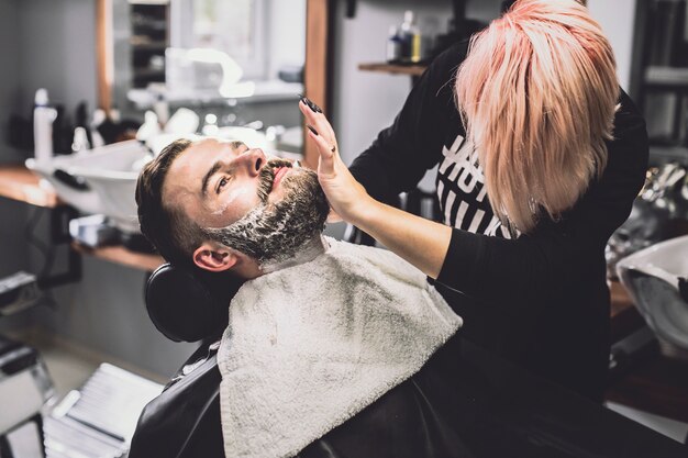 Woman shaving stylish customer