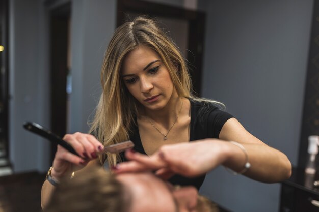 Woman shaving unrecognizable man