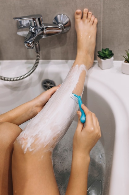 Женщина расчесывает ноги в ванной