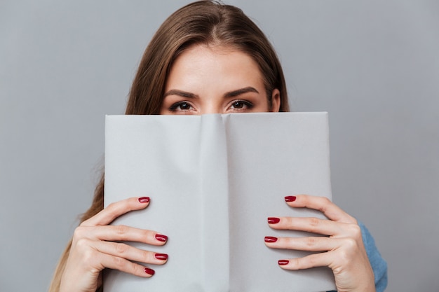 Woman in shirt hiding behind the book